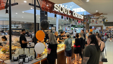 Storefront with balloons and a crowd of customers